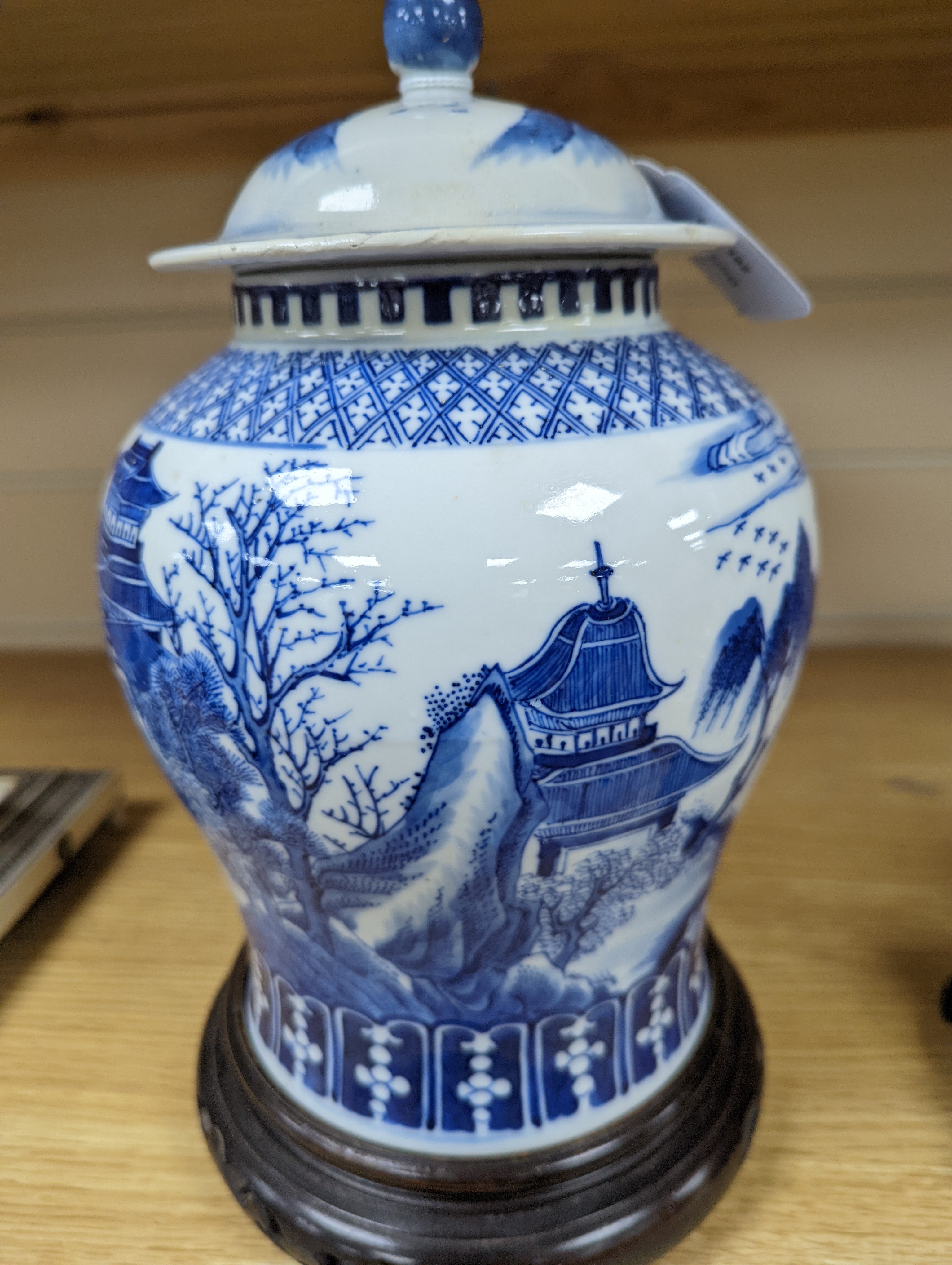 A late 19th / early 20th century Chinese blue and white landscape jar and cover, wood stand 30cm total height